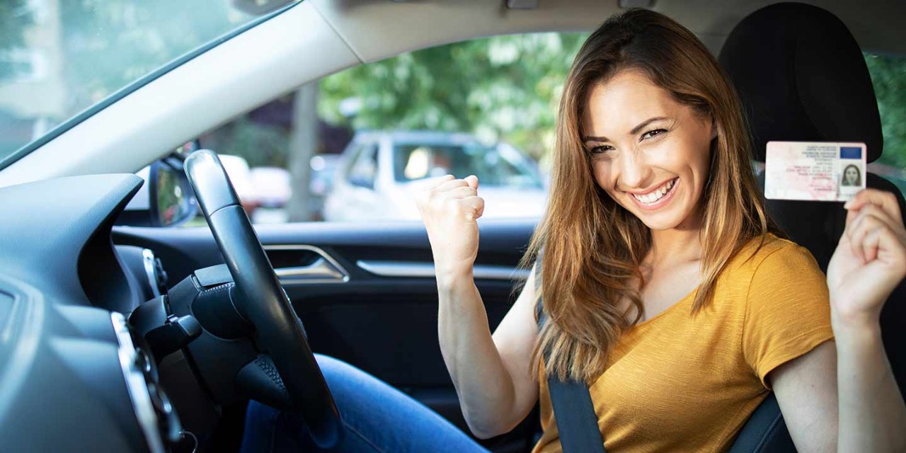 smiling young driver showing new driving licence