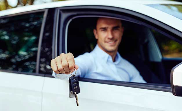 Business man showing key sitting in car