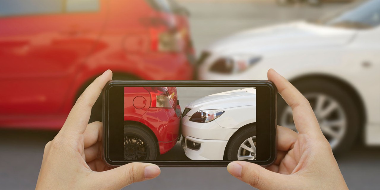 Close up hand of woman holding smartphone and take photo of car accident