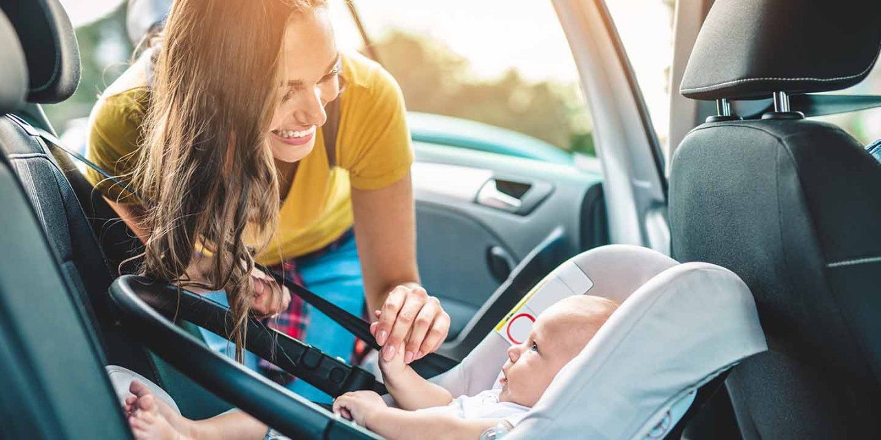mom smiling with baby on the child car seat