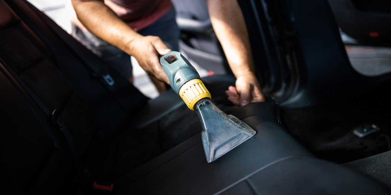 Car wash service worker wet cleaning vehicle interior and seats