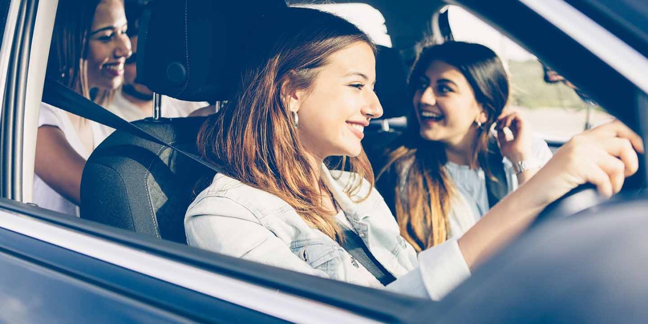 young woman driving the car with friends