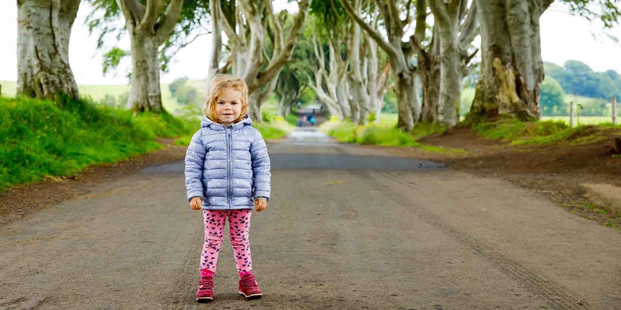  a small girl standing up in the Dark Hedges