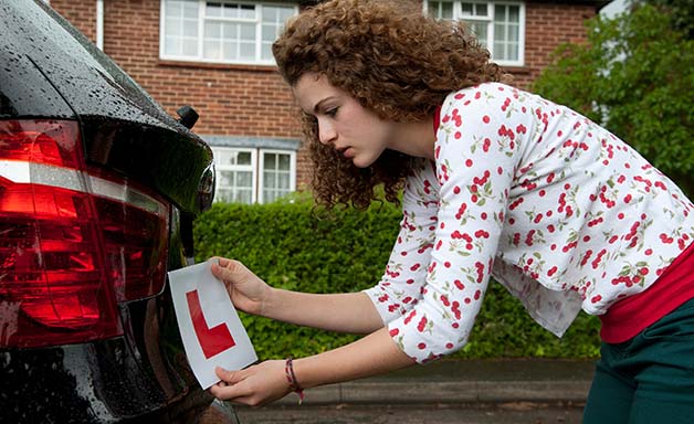 Young female driver attaching a L plate to car