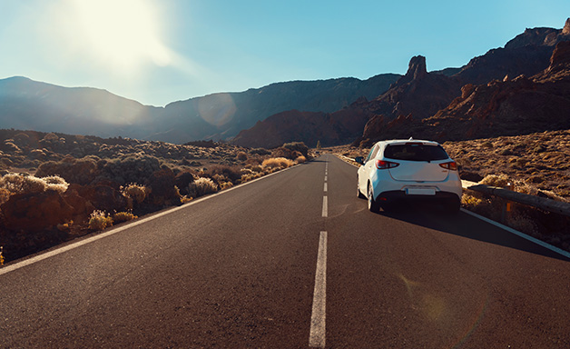 white car driving on highway through desert