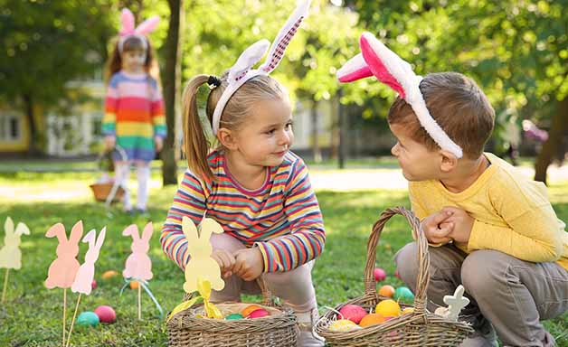 Cute little children hunting eggs in park