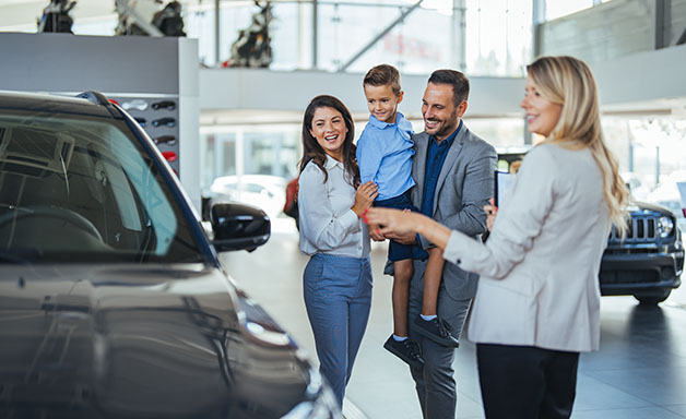 Saleswoman at car dealership centre helping family to choose new family vehicle