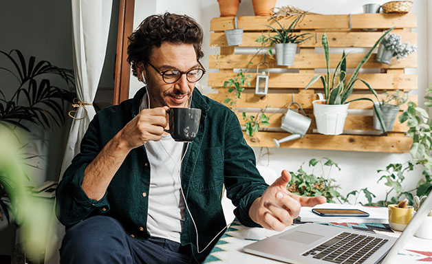 Cheerful man working online with laptop computer having a virtual meeting at home