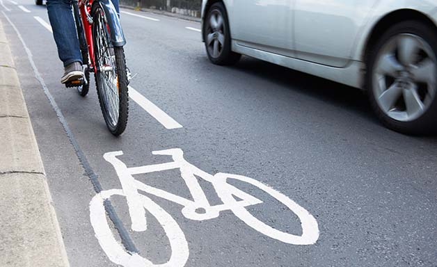 Cyclist riding on the bike lane alongside a car