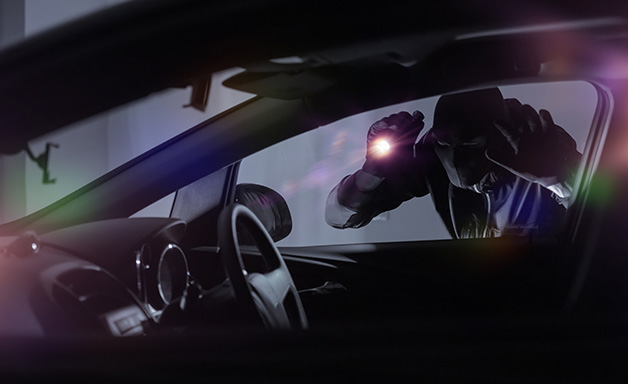 Inside view of the creepy thief wearing black mask , holding a flashlight, looking inside the car, dark night background